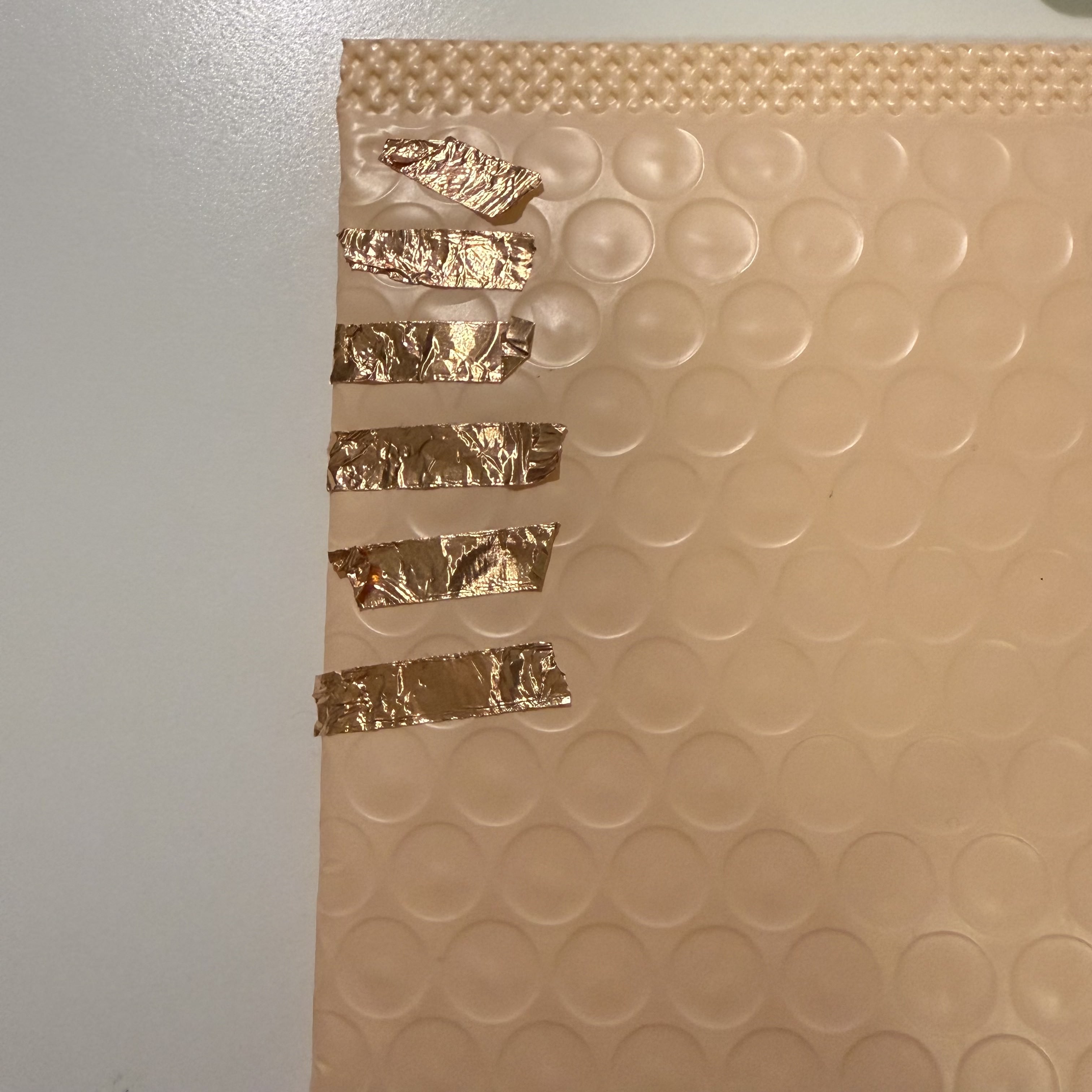 This image shows copper tape strips attached to a bubbly textured pad. I use this setup to control various functions on my computer through physical touch, making it a simple yet effective tool for interactive projects.
